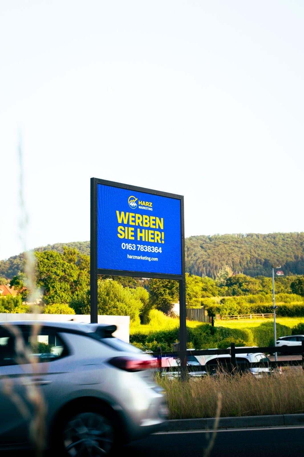 Digitale Werbetafel von Harz Marketing in Bad Harzburg mit der Anzeige „Werben Sie hier“ an einer stark befahrenen Straße
